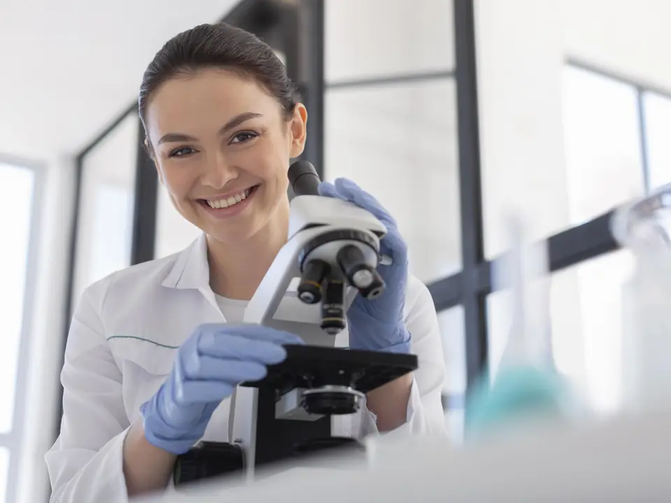 Patologista clínica ao microscópio em laboratório veterinário